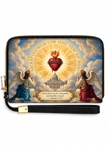 A zip-around wristlet clutch with a black wrist strap and gold-tone hardware, featuring a religious illustration of two kneeling angels flanking a radiant red heart on a golden sunburst, with clouds, a domed cathedral, and a Bible verse printed on the front.