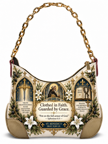 A hobo-style shoulder bag with a gold chain strap, featuring a printed St. Benedict religious design with text, floral motifs, and saint imagery on a white background.