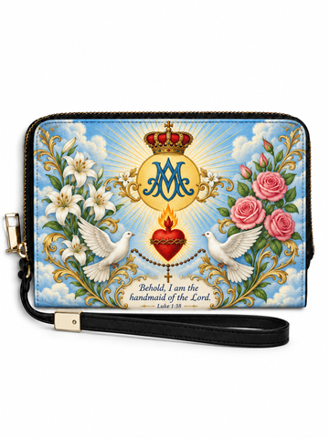 A zip-around wristlet wallet with a black wrist strap, featuring a colorful religious design with a crown, radiant heart, two white doves, pink roses, white lilies, and a blue monogram 'M' on a light blue sky background.