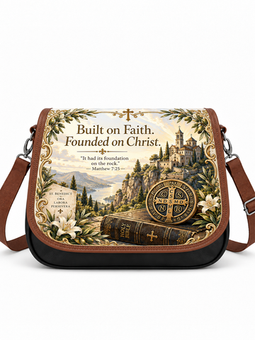 A messenger-style shoulder bag with a brown leather strap and black base, featuring a large printed religious illustration on the front flap. The artwork shows a castle in a mountain landscape, white lilies, a vintage book with a cross, a circular cross emblem, and the text 'Built on Faith.