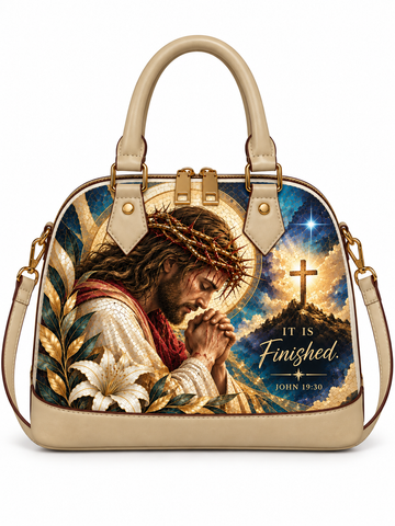 A structured beige handbag with a large printed religious graphic on the front showing Jesus in a crown of thorns beside a cross and the text 'IT IS Finished. JOHN 19:30'.