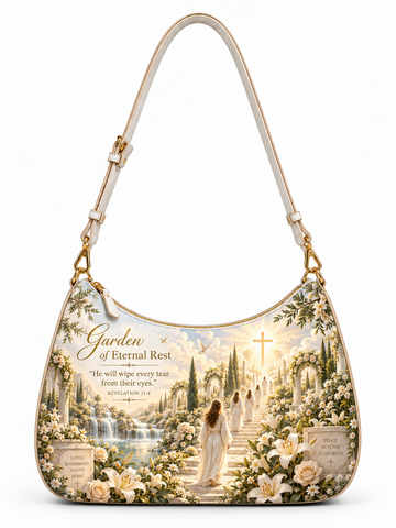 A shoulder bag with a detailed religious illustration on the front depicting a woman walking up a path toward a cross in a garden of flowers and graves, with the text 'Garden of Eternal Rest' and a Bible verse. The bag has a cream strap and trim with gold-tone hardware.