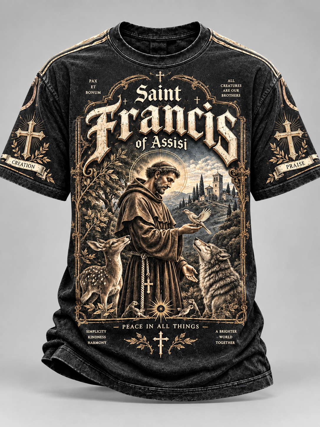 A black short-sleeve graphic t-shirt featuring a detailed vintage-style illustration of Saint Francis of Assisi, with deer, a wolf, a castle, and ornate gold-toned text on a gray studio background.