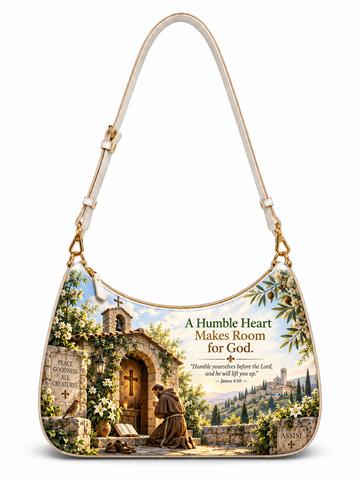 A shoulder bag with a cream-colored strap and trim, featuring a detailed scenic print of a stone monastery and a kneeling figure, alongside the text 'A Humble Heart Makes Room for God.' and a Bible verse.