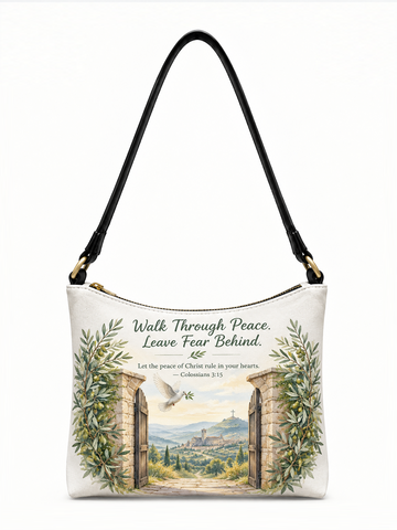 A white shoulder bag with a black strap and gold-tone hardware, featuring a printed illustration of stone archways, green vines, a dove, and a scenic landscape. The text on the bag reads, 'Walk Through Peace.