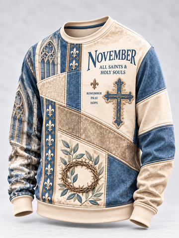 A long-sleeve crewneck sweatshirt with a vintage-style patchwork design in beige and blue. The front features the text 'NOVEMBER ALL SAINTS & HOLY SOULS', a blue cross, a floral crown of thorns, and fleur-de-lis motifs.