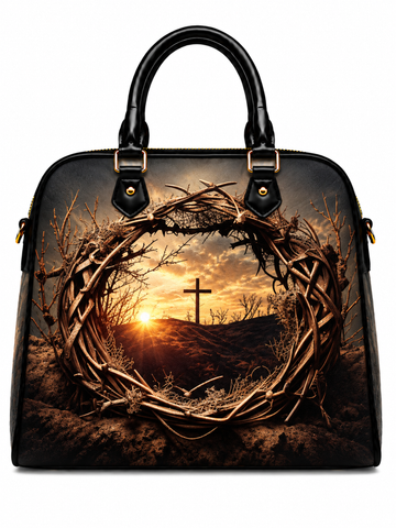 A structured black handbag with dual top handles, featuring a printed graphic of a crown of thorns framing a sunset landscape with a cross on a hill.
