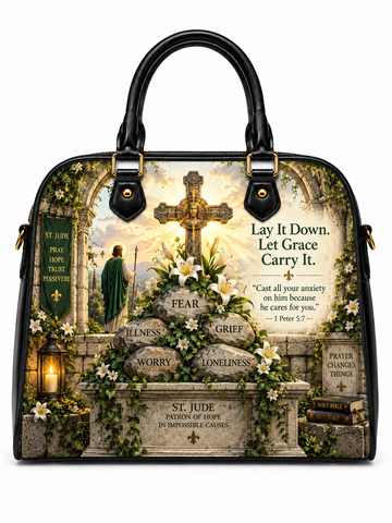 A structured black handbag with double top handles, featuring a detailed printed graphic of a cemetery scene with a cross, tombstones, white lilies, and inspirational religious text on a white background.
