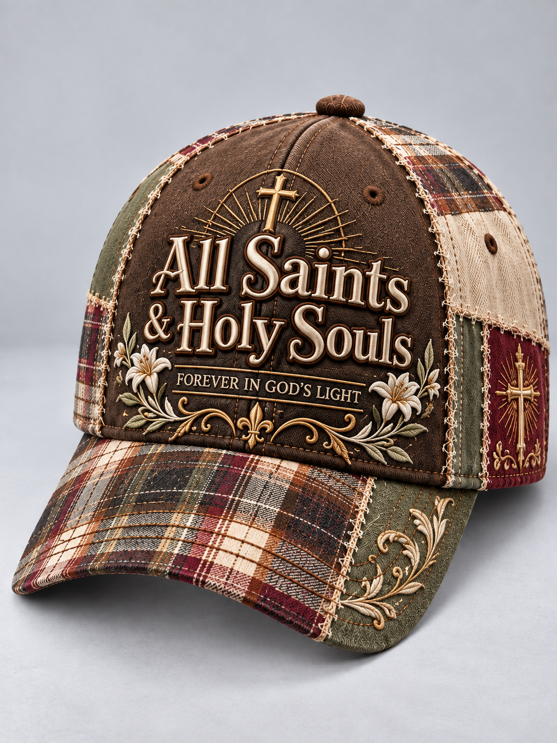 A baseball cap with a brown front panel featuring the text 'All Saints & Holy Souls' and 'FOREVER IN GOD'S LIGHT' with a gold cross and sunburst. The sides and brim feature a patchwork plaid pattern in brown, red, green, and beige with embroidered gold details.