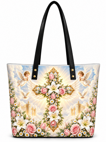 A tote bag with black shoulder straps and a detailed religious print featuring a golden cross adorned with lilies and pink roses, surrounded by white doves, clouds, and small white daisies, on a plain white background.