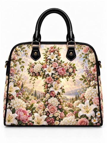 A structured handbag with black leather handles and trim, featuring a detailed floral and landscape print on the body. The design showcases a large cross made of pink and white flowers, surrounded by roses, lilies, and wildflowers over a scenic background.