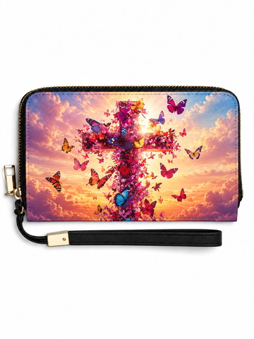 A zip-around wristlet wallet with a black wrist strap and gold-tone hardware, featuring a vibrant printed design of a cross made of flowers and butterflies against a colorful sunset sky.