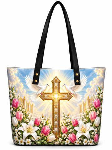 A tote bag with black handles, featuring a vibrant printed design of a golden cross, two white doves, pink and white lilies, and a bright sky background.