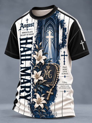 A short-sleeve crewneck t-shirt with a complex religious graphic print. The design features a split background of dark blue and off-white, with a gothic cathedral window, a rosary, white lilies, a monogrammed heart of Mary, and gothic typography including 'HAIL MARY' and 'August'.